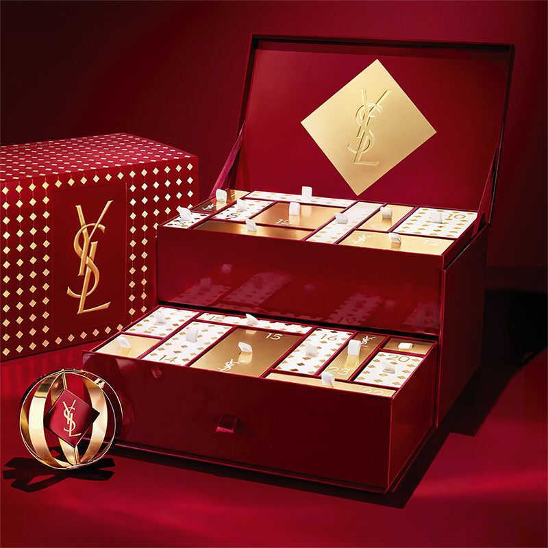 Calendario de Adviento de belleza de YSL con cosmeticos y perfumes en un expositor rojo y dorado.