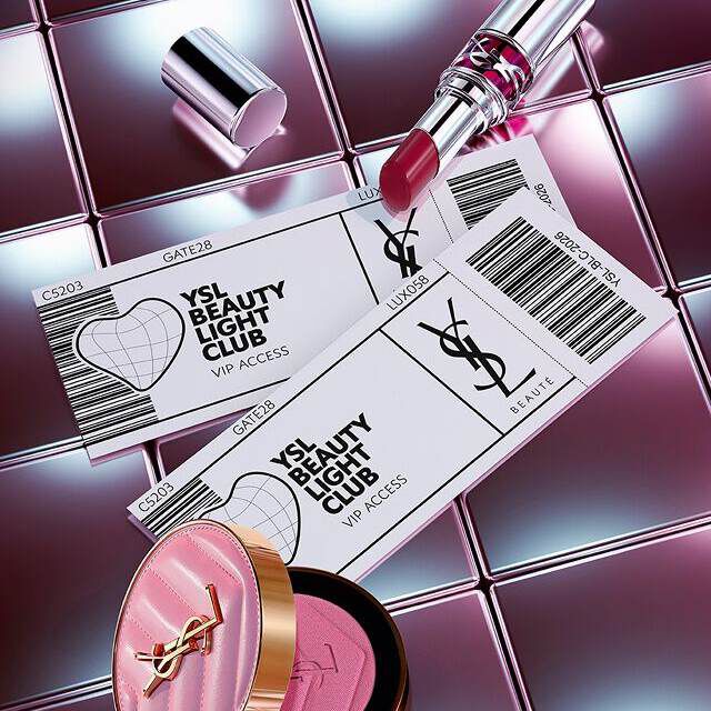 Productos de belleza YSL (labial y colorete) dispuestos con tarjetas de acceso VIP estilo billete sobre una superficie metalica reflectante.