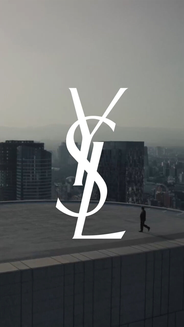 Logo de YSL sobre azotea con skyline al atardecer