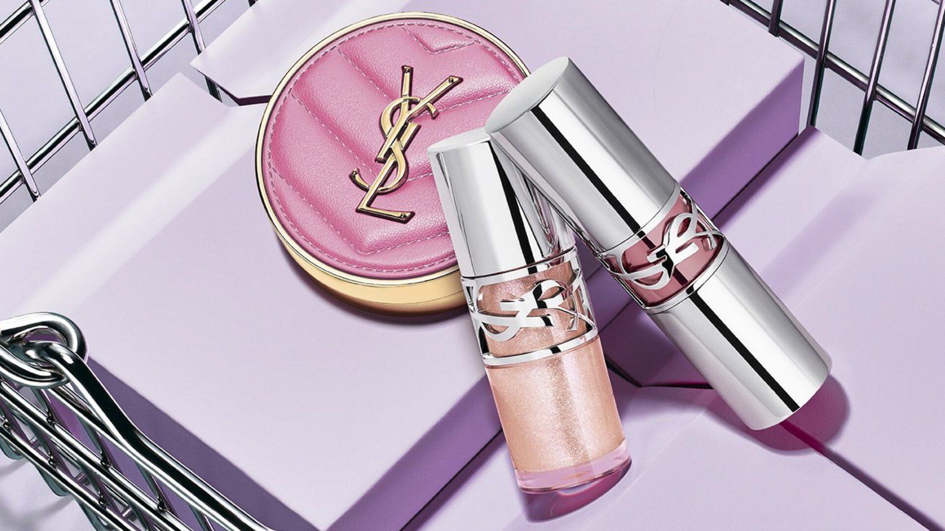 Compacto rosa y labiales YSL en una cesta de compra plateada.