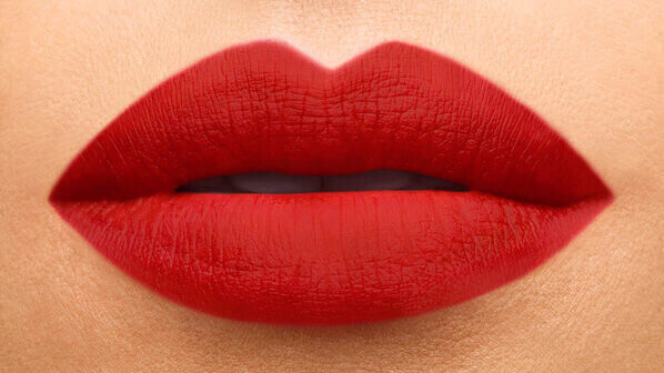 Close-up of a pair of full lips painted with vibrant red lipstick.