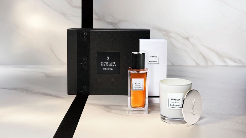 A stylish gift set featuring a bottle of perfume and a scented candle, elegantly presented in a black box with a sleek design on a marble surface.