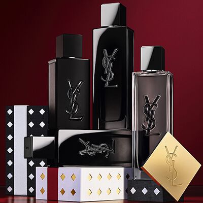 Estuches de regalo de la coleccion navidena de Yves Saint Laurent y productos de belleza de lujo sobre fondo rojo festivo.
