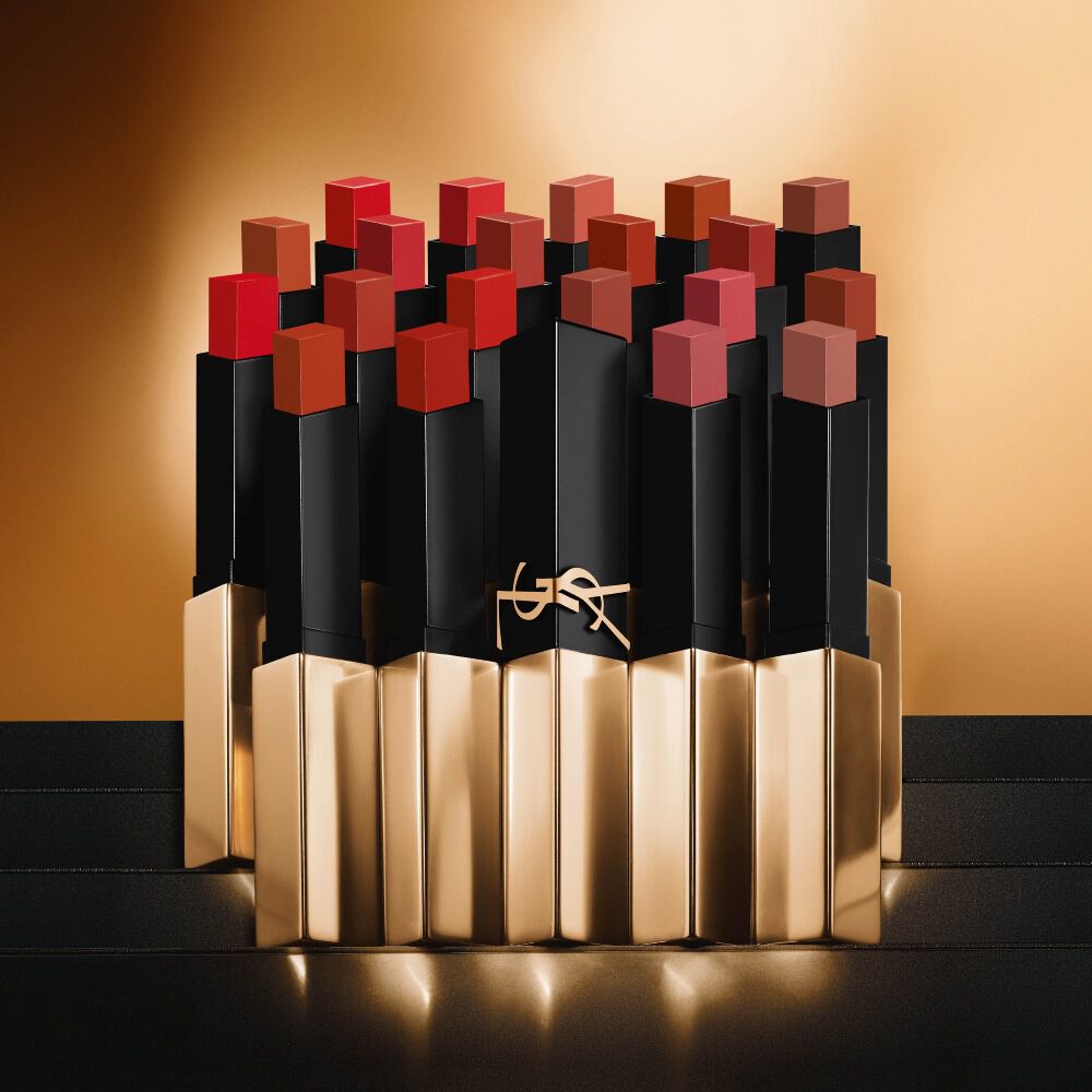 Varios labiales delgados y cuadrados de Yves Saint Laurent en tonos rojos y nude sobre un fondo dorado.