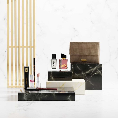 Productos de belleza YSL sobre pedestales de marmol de lujo.