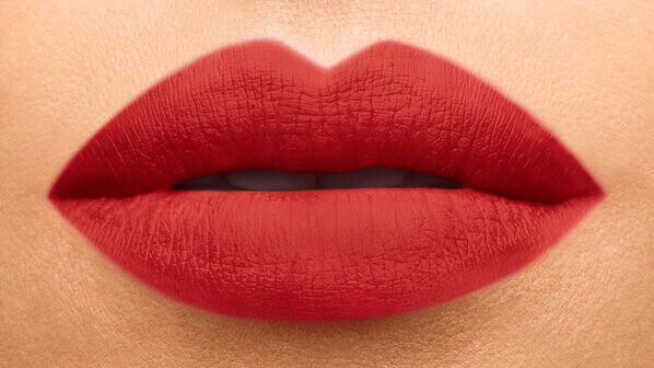 Close-up of full, matte red lips against a light background.