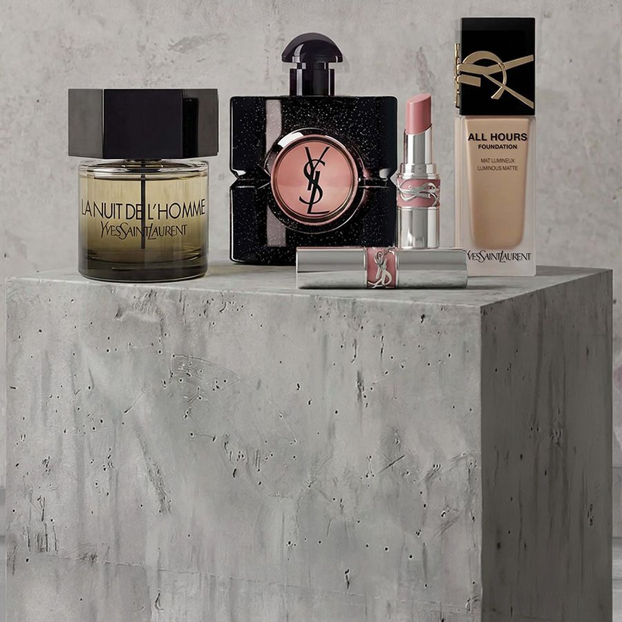 Exposicion promocional de productos de maquillaje de YSL Beaute que incluye mascara de pestanas, una paleta de sombras de ojos acolchada y pintalabios sobre un fondo de hormigon.