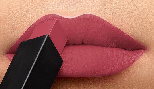 Close-up of lips applying a mauve lipstick from a rectangular tube.