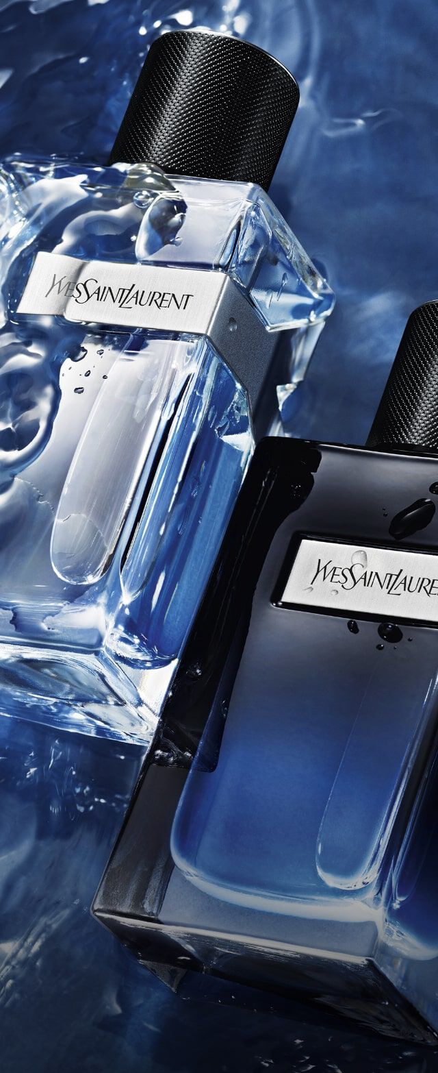 Frascos de perfume de Yves Saint Laurent, uno transparente y otro oscuro, sobre un fondo de agua azul.
