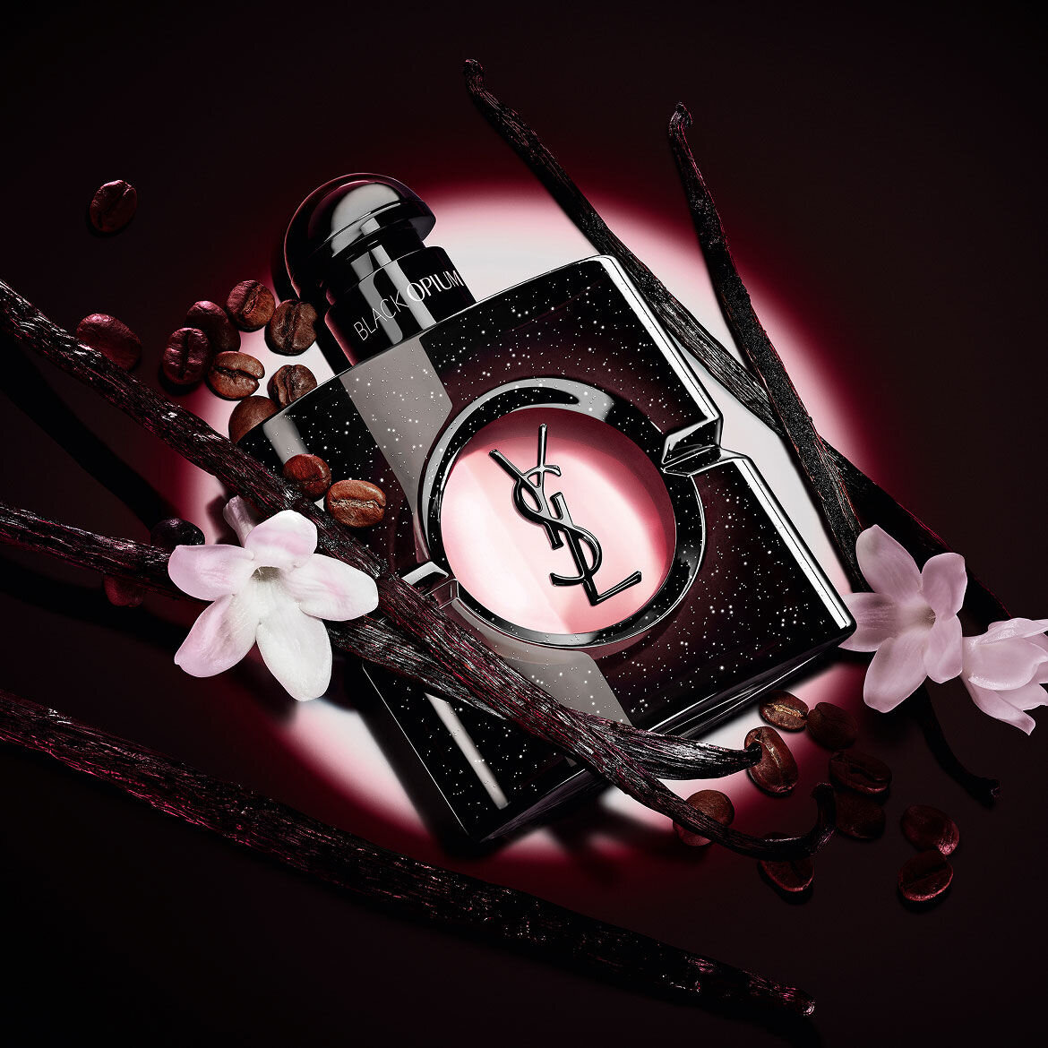 Frasco de Black Opium Eau de Parfum con flores de jazmin blanco, vainas de vainilla y granos de cafe tostado.