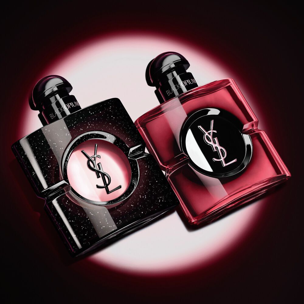 Dos frascos de perfume Black Opium de Yves Saint Laurent iluminados sobre fondo oscuro.
