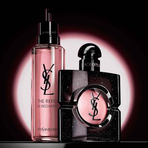 Una mano sostiene un frasco de recambio dorado sobre un fondo neutro. A la izquierda, un texto blanco de estilo pincel dice "Unete al movimiento REFILL" y a la derecha se muestra un frasco de fragancia de cristal clasico de YSL Libre con su caracteristico logotipo dorado.