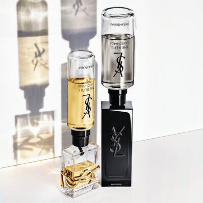 Dos frascos de perfume Yves Saint Laurent (uno claro y otro oscuro) con sus cartuchos recargables.