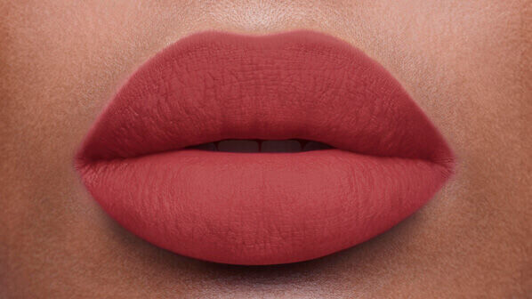 Close-up of a pair of full lips coated in a matte rosy lipstick, showcasing a smooth texture and soft color.