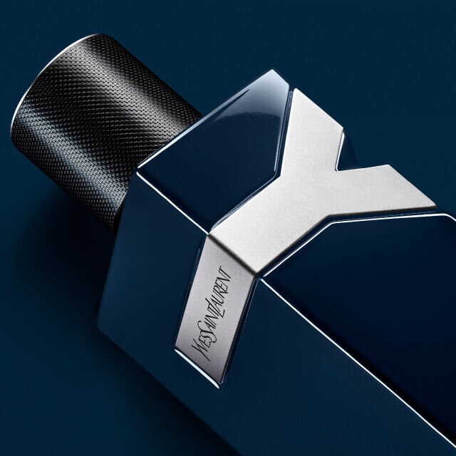 A close-up of a sleek blue and silver fragrance bottle with a modern design, featuring a textured black cap and the brand name engraved on the side.