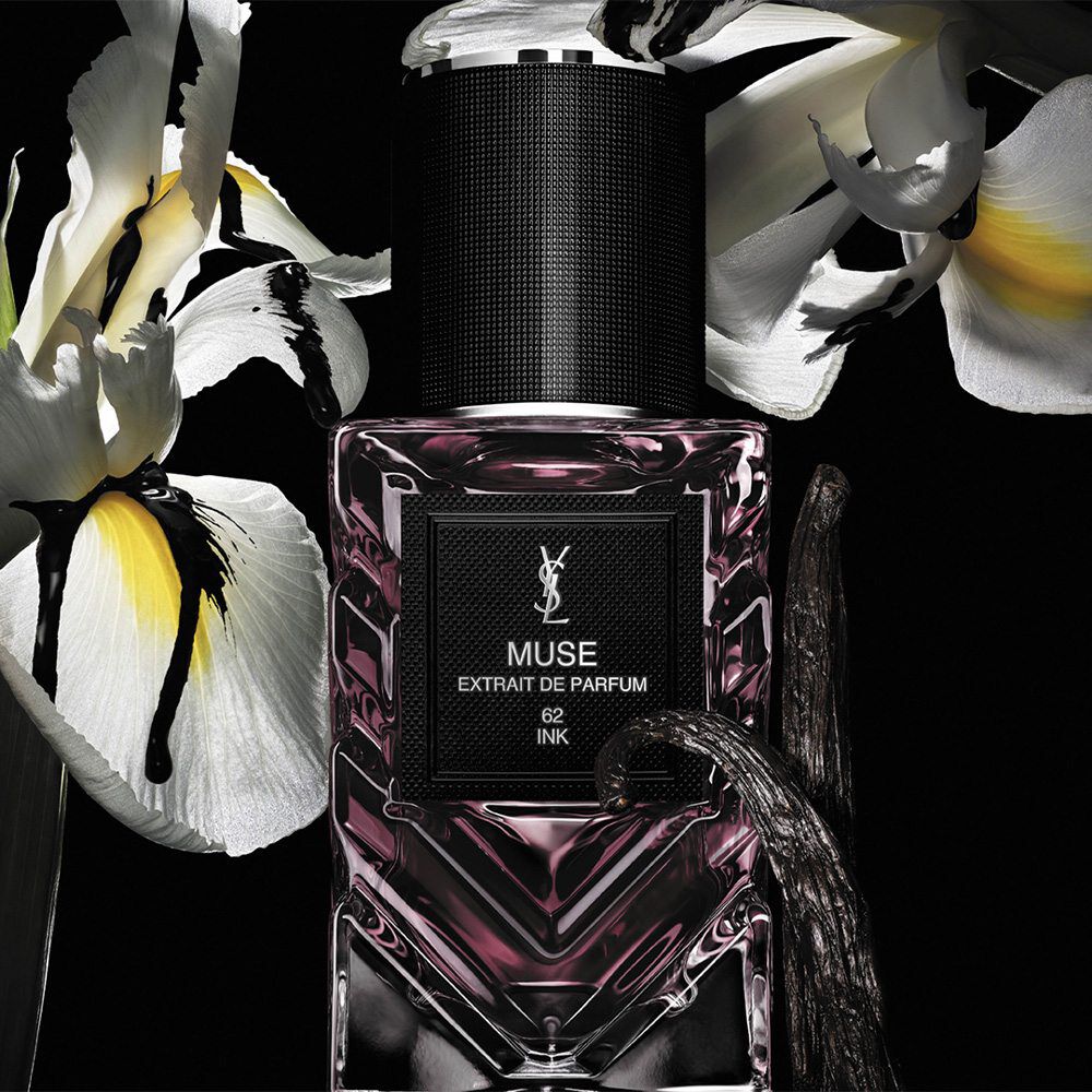Frasco de Le Vestiaire des Parfums nuevo sobre fondo negro y flores detras.