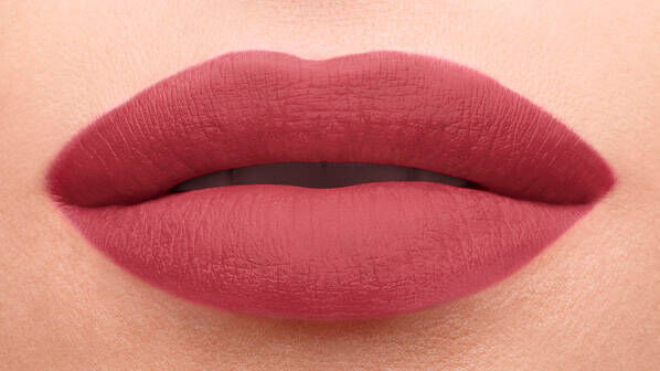 Close-up of a pair of full lips wearing a matte mauve lipstick, with a smooth texture and defined shape.