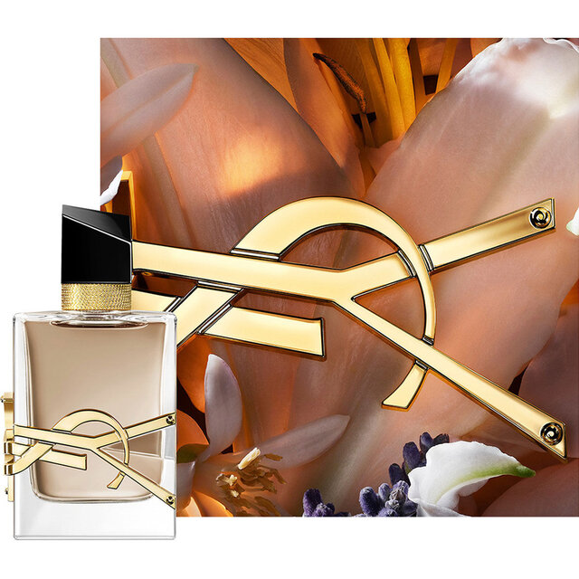 Frasco LIBRE FLOWERS & FLAMES enmarcado por petalos cremosos y el logo YSL dorado bajo una luz calida.