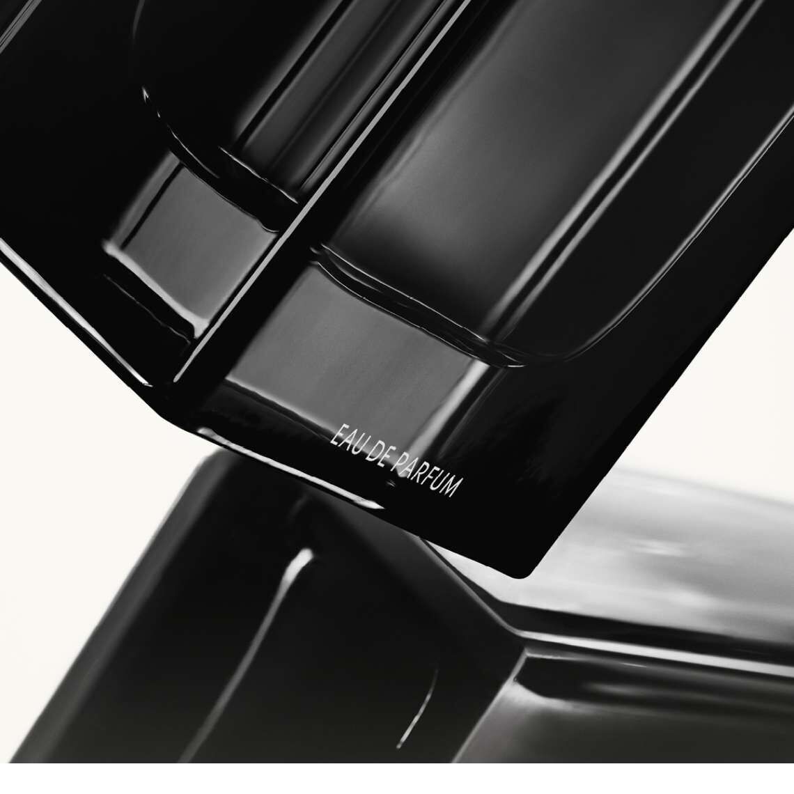 A close-up of a sleek black perfume bottle, featuring the label "EAU DE PARFUM" in a minimalist design.