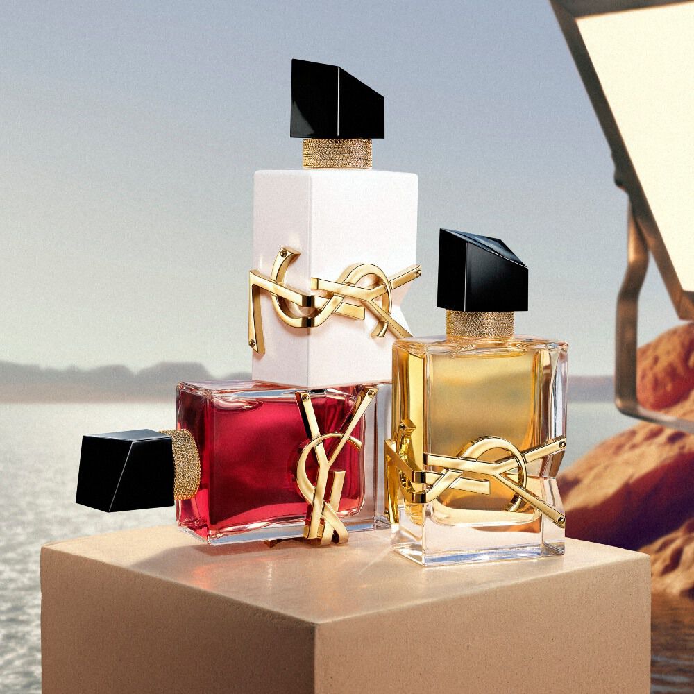 Frascos de fragancia YSL colocados sobre un pedestal frente a un paisaje desertico.