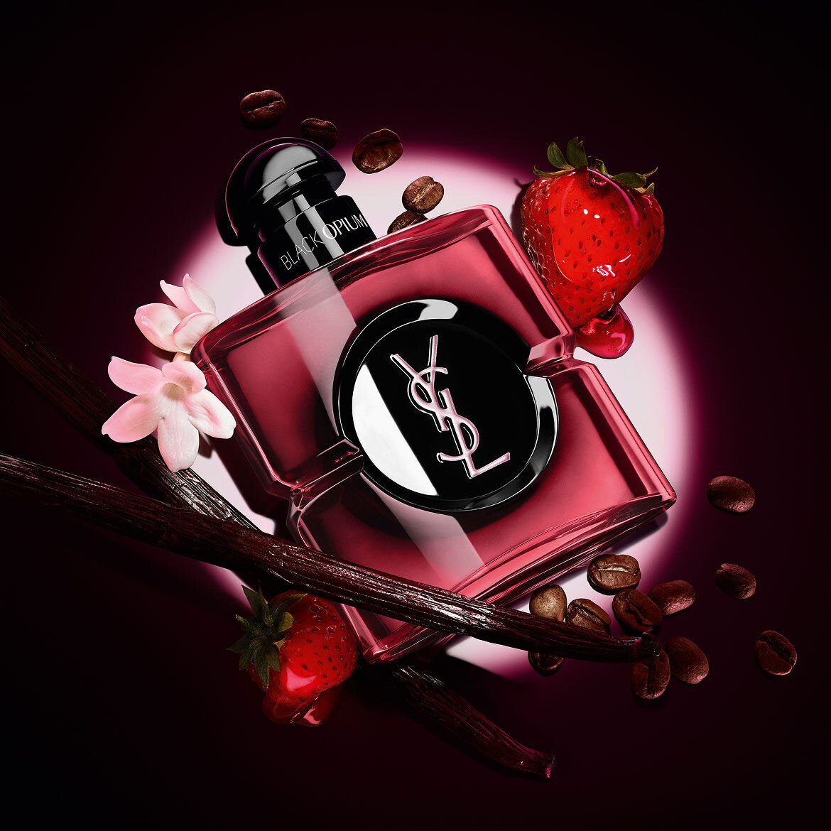 Frasco de Black Opium Eau de Parfum Pink Glaze rodeado de fresas frescas, vainas de vainilla, granos de cafe y jazmin.