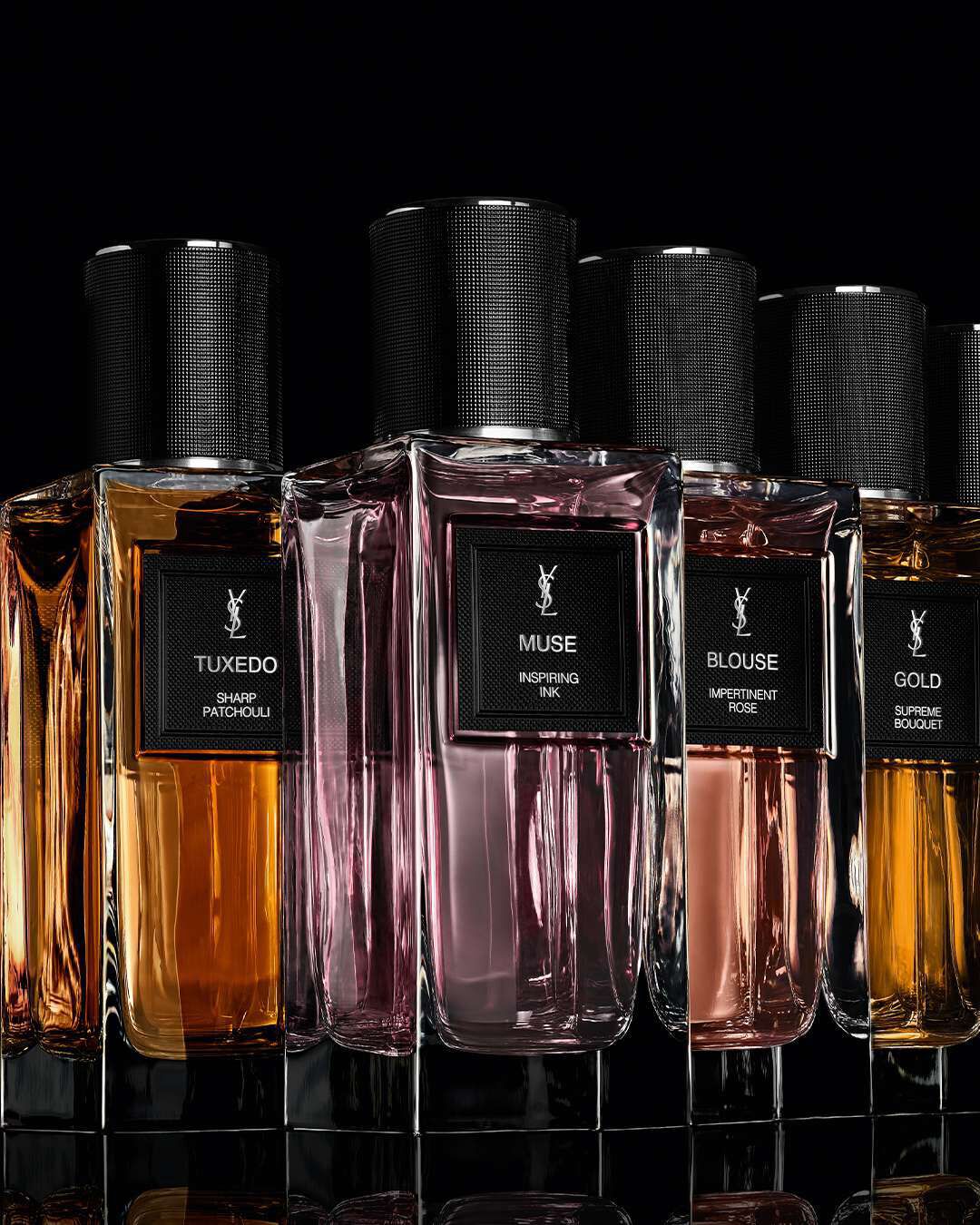 A collection of elegant perfume bottles lined up against a dark background, showcasing various scents with distinct labels and vibrant liquid colors.