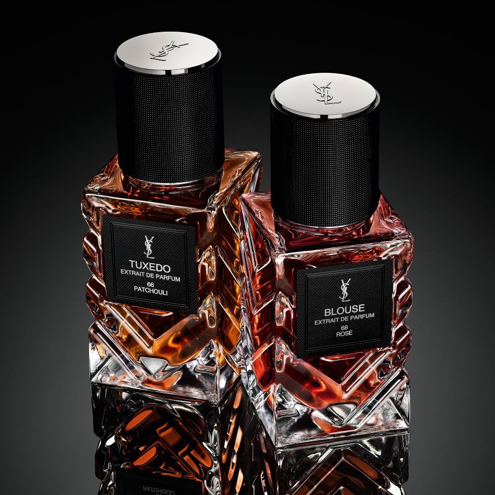 Una coleccion de frascos de la fragancia "Le Vestiaire des Parfums" de Yves Saint Laurent dispuestos en forma de diamante sobre una superficie negra reflectante.