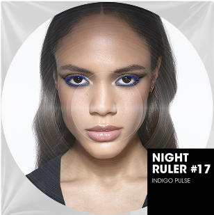 Un retrato en color de cerca de una mujer con cabello largo y liso castano y tez clara. Sus ojos estan intensamente maquillados con un delineador azul electrico vibrante y una sombra de ojos bronce. Sus labios son naturales y brillantes. En la parte inferior derecha de la imagen circular, una incrustacion rectangular negra indica "NIGHT RULER #17" y "INDIGO PULSE", sugiriendo una coleccion o un ambiente energetico y audaz, como un titulo de cancion.