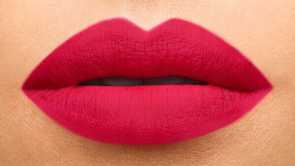 Close-up of luscious, full lips painted in a bright pink matte lipstick, showcasing smooth texture and defined shape.