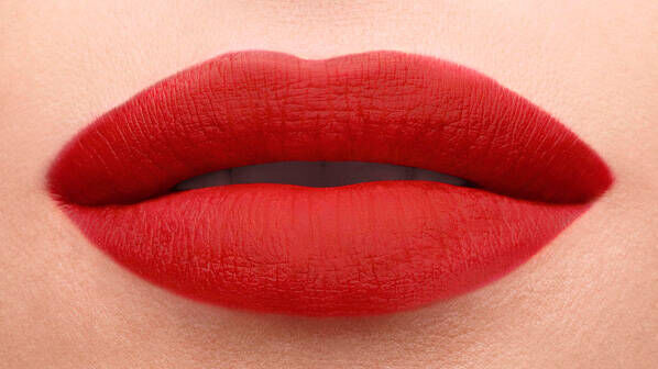 Close-up of a pair of full lips painted in a bold red lipstick.