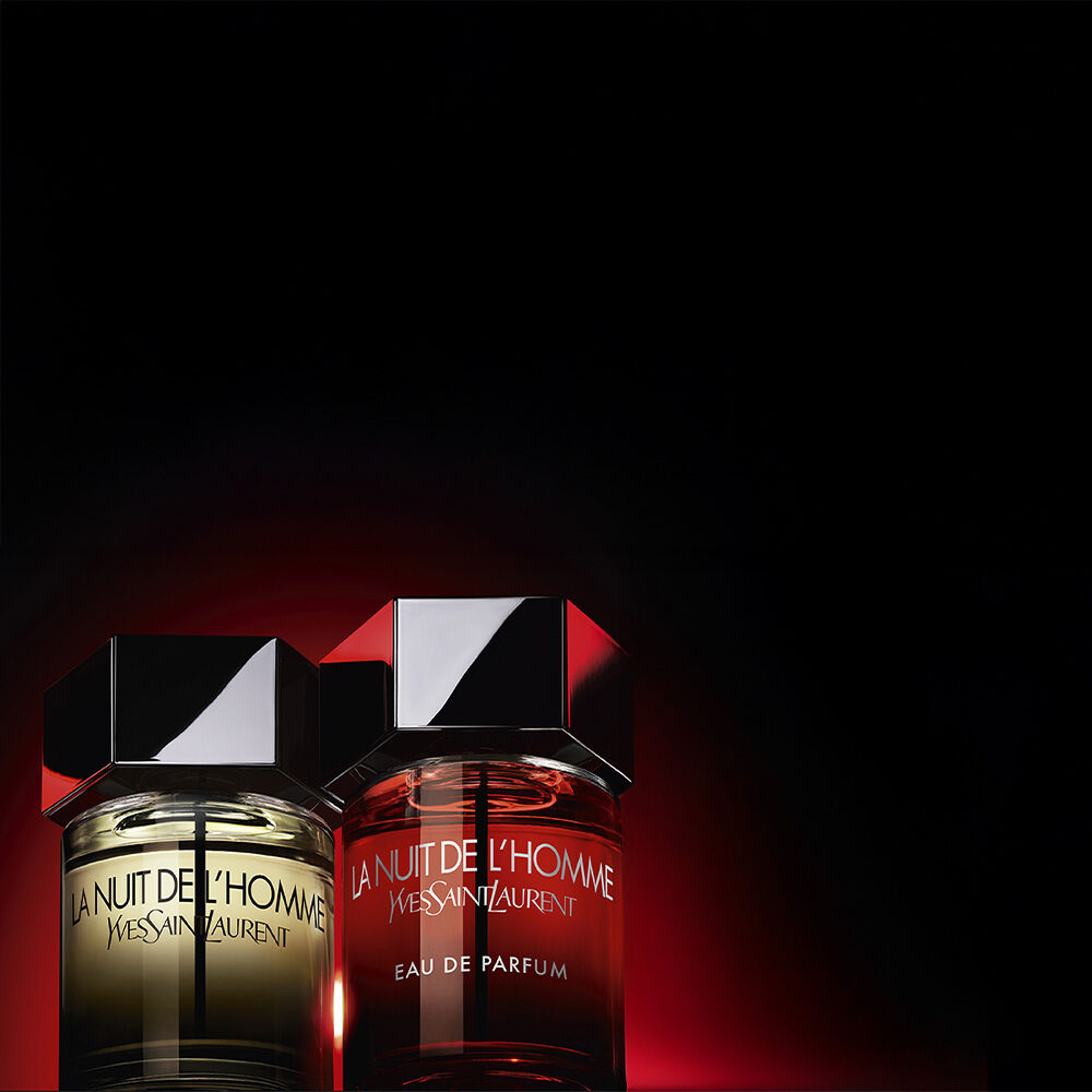 Frascos YSL La Nuit de l’Homme sobre fondo rojo oscuro.