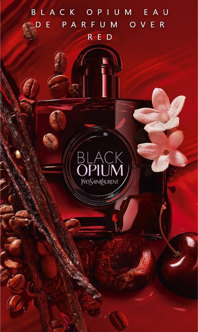 Frasco de perfume "Black Opium" de Yves Saint Laurent sobre un fondo rojo, acompanado de granos de cafe, ramitas y flores blancas.