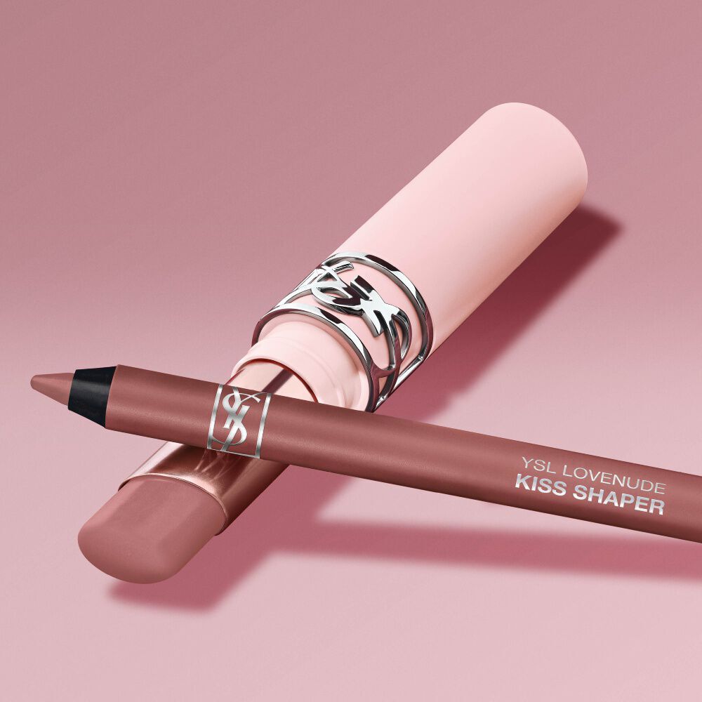 YSL LOVENUDE Kiss Shaper and Lip Blusher en el tono 1, naturaleza muerta digital sobre un fondo rosa suave.