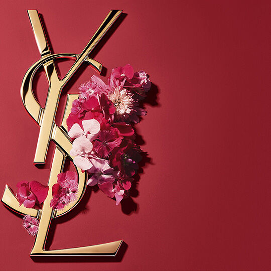 Logo YSL dorado con flores rosas sobre fondo rojo