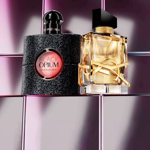 Productos de belleza YSL que incluyen una polvera acolchada, mascara de pestanas y dos labiales sobre fondo de azulejos rosas brillantes.