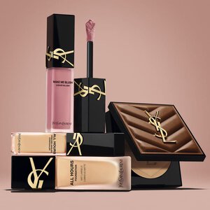 Productos de belleza de YSL, incluido un blush, una base de maquillaje y un polvo compacto, sobre fondo nude.
