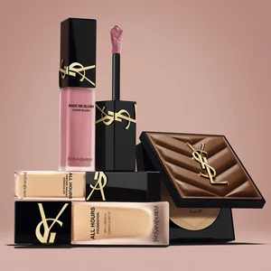 Productos de belleza de YSL, incluido un blush, una base de maquillaje y un polvo compacto, sobre fondo nude.