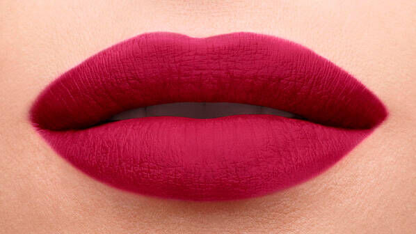Close-up of a pair of full lips painted with a rich, deep red lipstick, showcasing a smooth and matte finish.