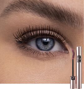 A close-up of a woman's eye with long, defined eyelashes, showcasing a mascara tube next to it. The eye has a striking blue hue.