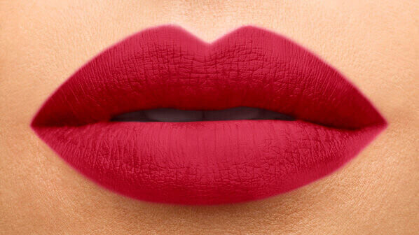 Close-up of a pair of full, well-defined lips coated in a deep red lipstick, with a smooth texture and a natural skin tone backdrop.