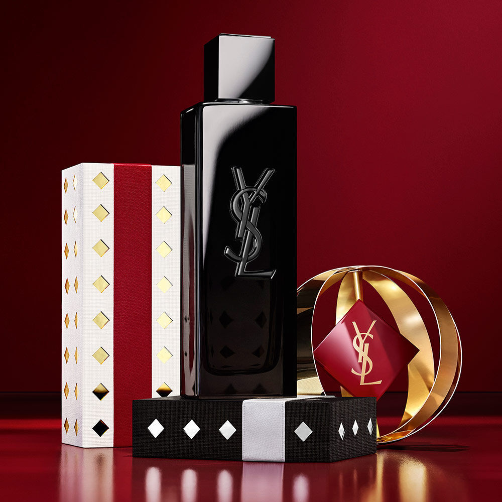 Frasco de la fragancia MYSLF junto a packaging navideno de YSL en dorado y burdeos.