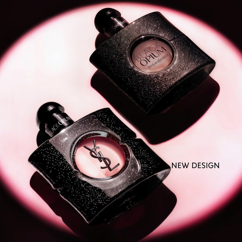 Frasco de Black Opium Eau de parfum tumbado de lado sobre una superficie oscura con un halo de luz rosa.