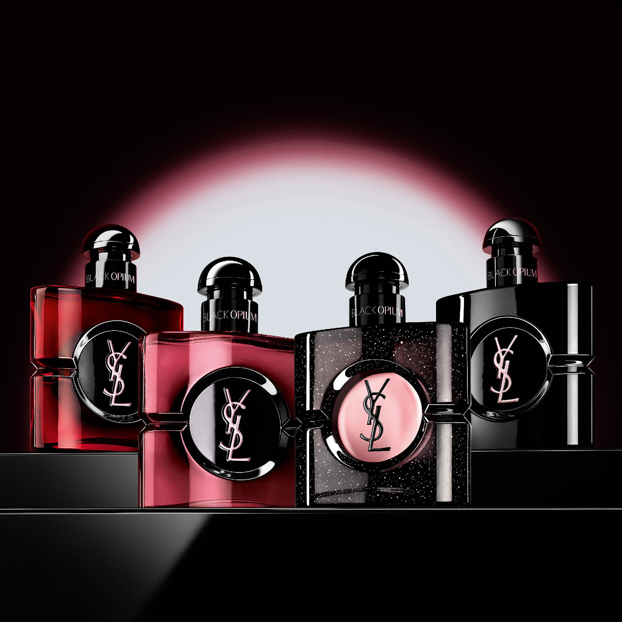 Cuatro frascos diferentes de perfume Black Opium colocados en
                        fila sobre una superficie oscura y reflectante.