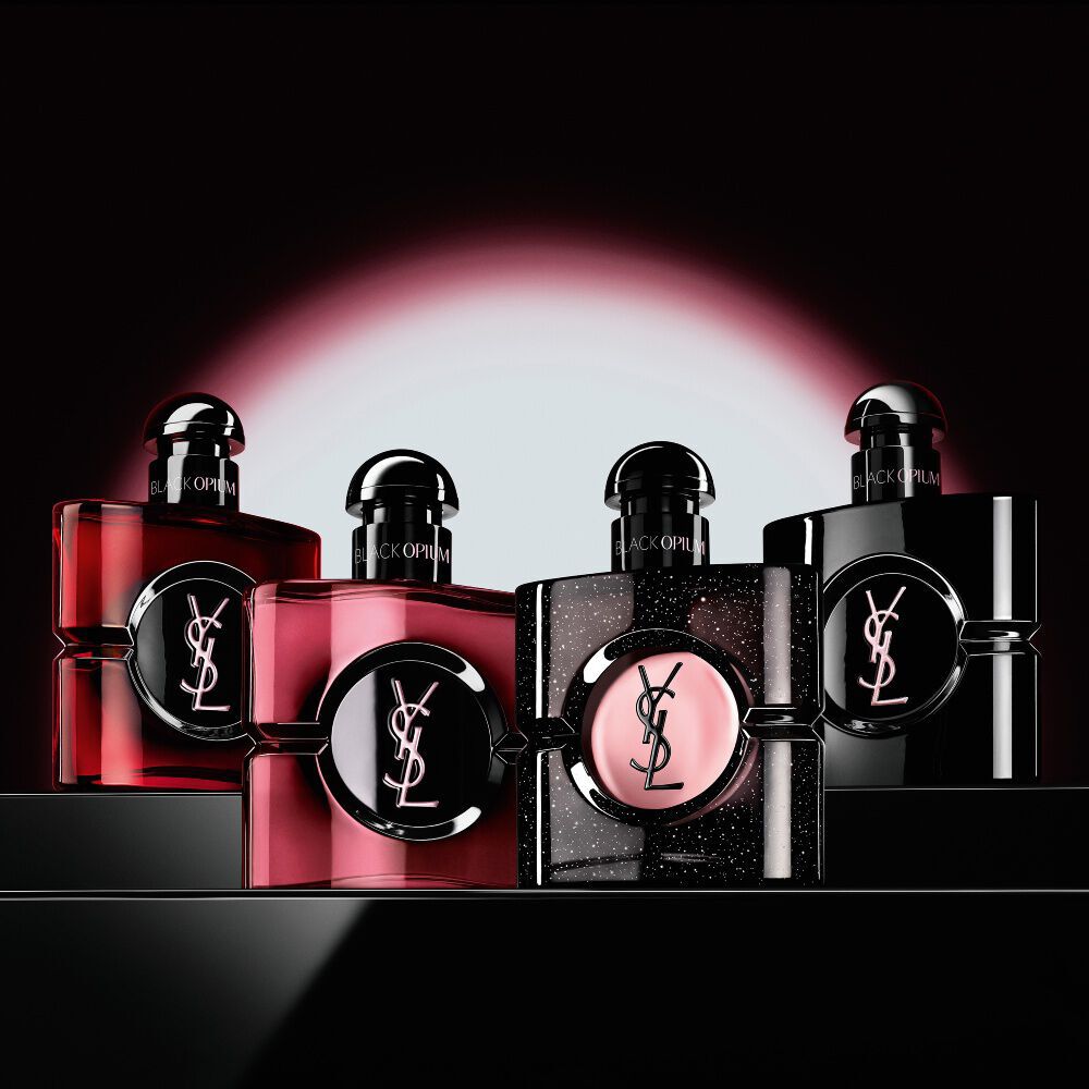 Cuatro frascos de perfume Black Opium diferentes alineados sobre una superficie oscura y reflectante.