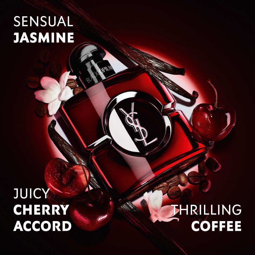 Frasco Black Opium Over Red en laca rojo intenso, rodeado de cerezas rojas frescas y granos de cafe con reivindicaciones.