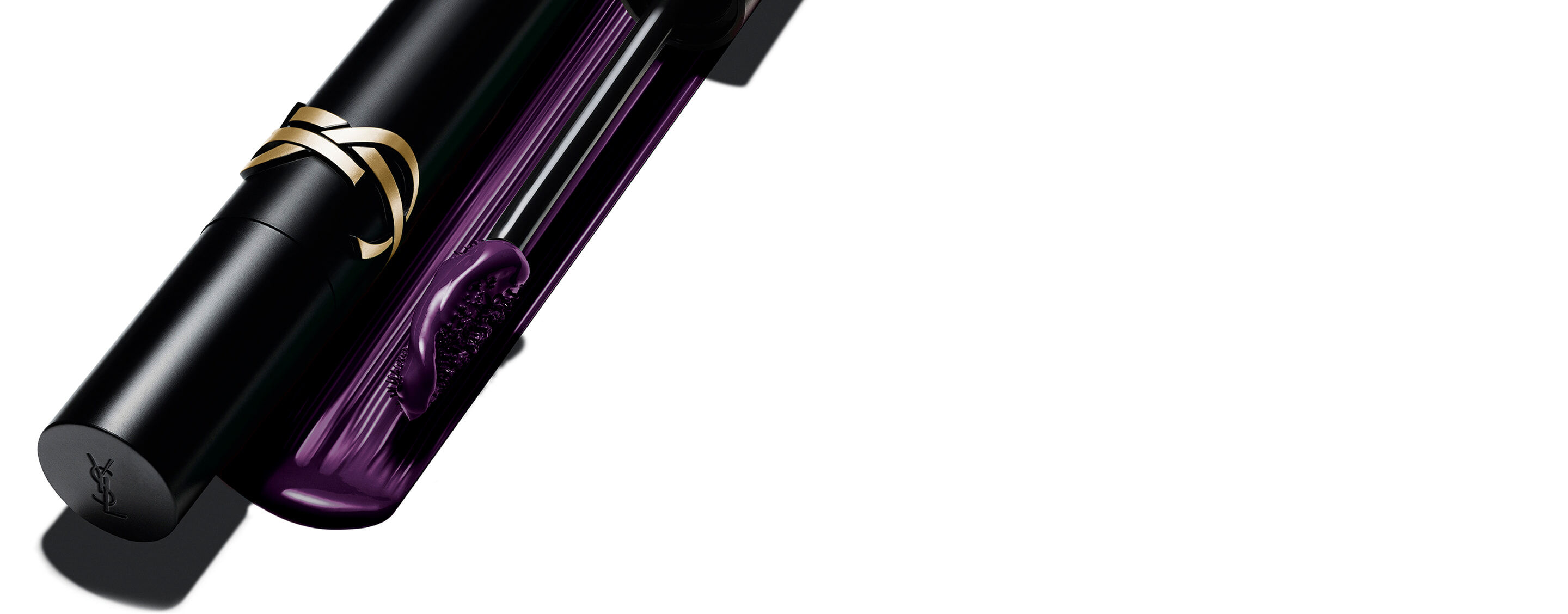 Máscara de pestañas Lash Clash de Yves Saint Laurent en tono ciruela, con el pack negro y logo YSL dorado y el cepillo que muestra la textura violeta.