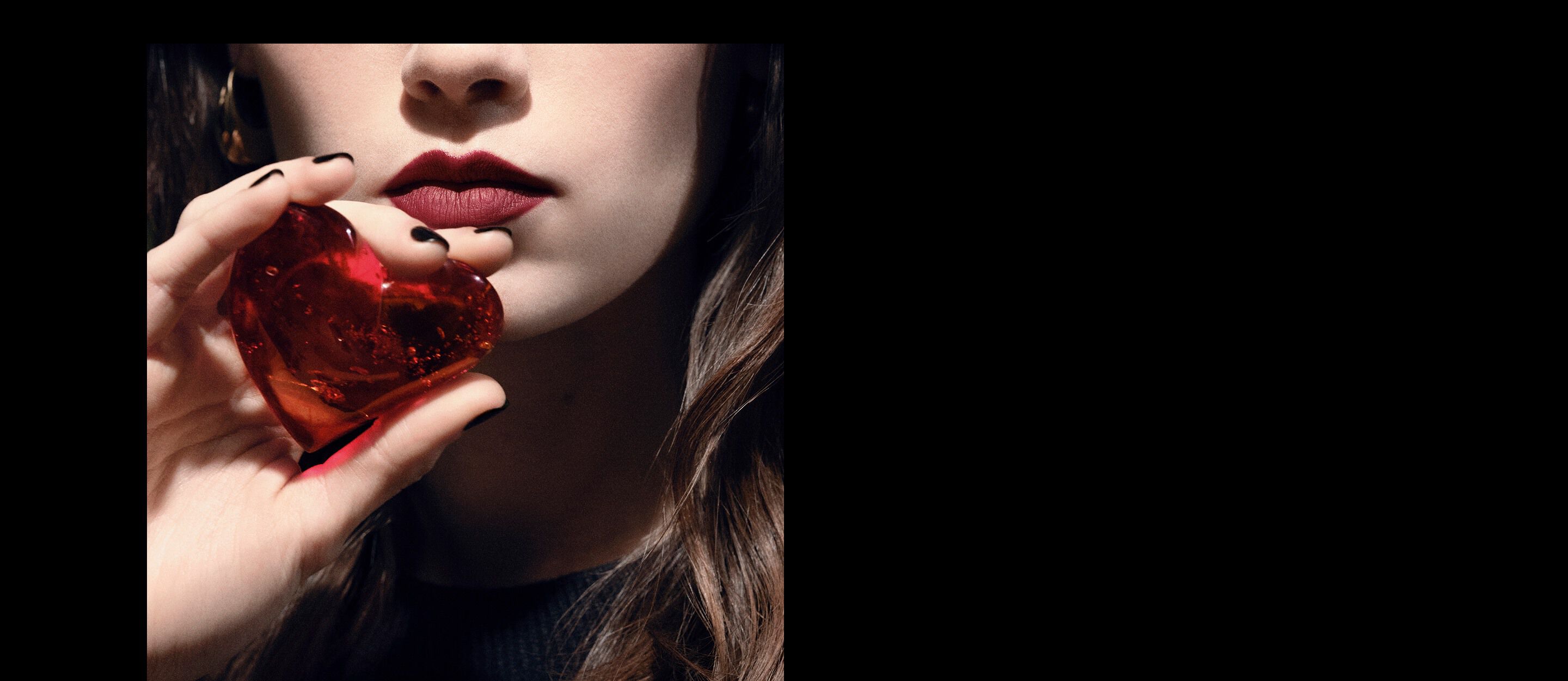 Primer plano de los labios y la mano de una modelo
sosteniendo una joya de corazón rojo rubí
translúcida para YSL CŒUR Eau de Parfum.