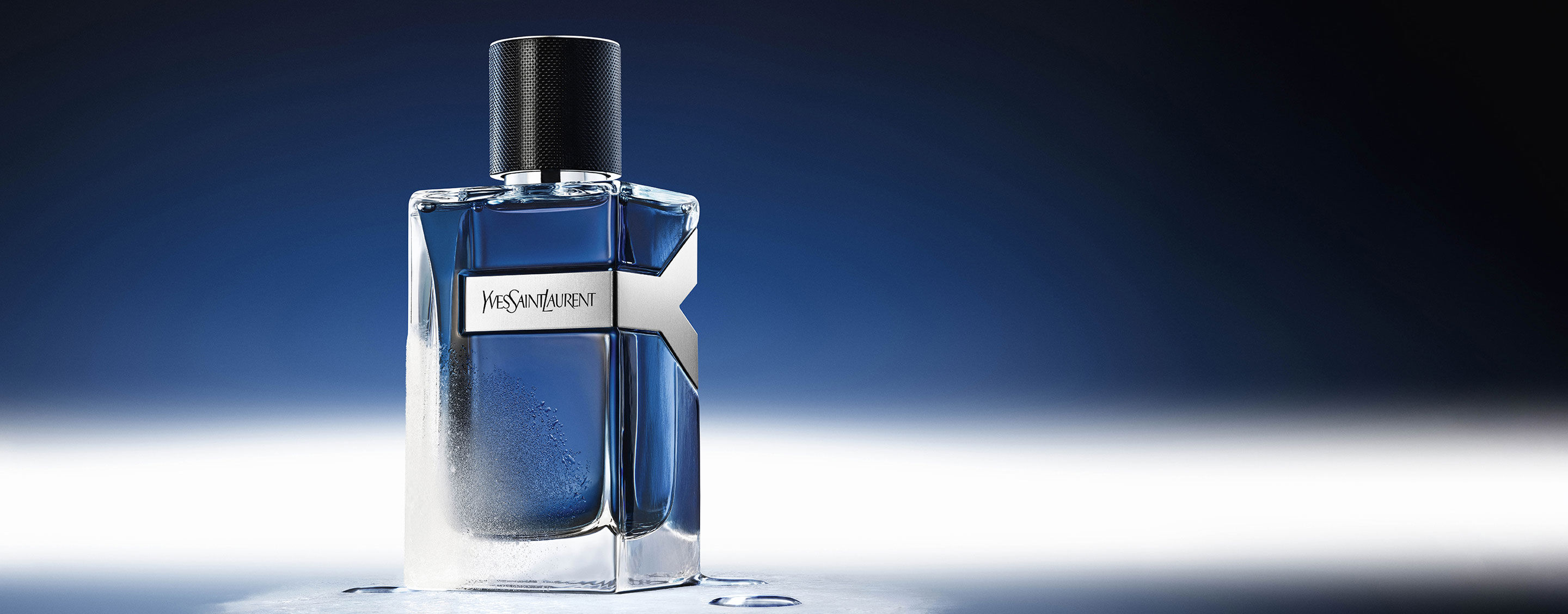 Frasco de 100 ml de YSL Y Eau de Toilette Intense Iced Cologne, escarchado y con gotas de agua, que refleja un ambiente azul gélido.