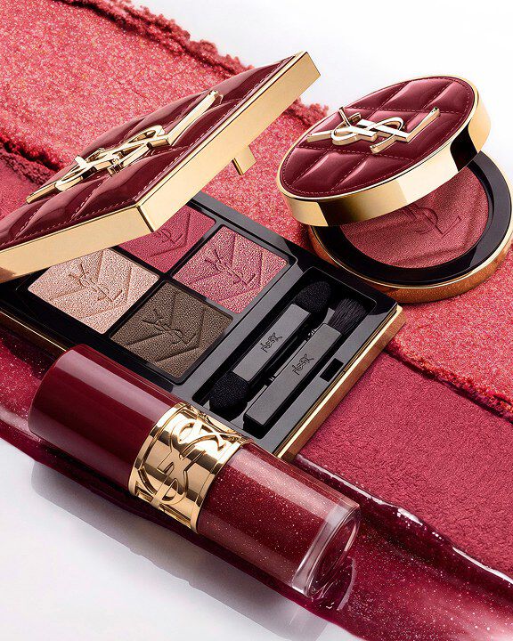 Dúo de maquillaje navideño YSL sobre trazos de textura burdeos con paleta y gloss