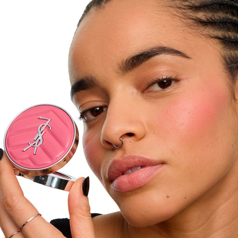 Primer plano de una modelo sosteniendo el *YSL Make Me Blush Lifted Glow Cream Blush*, mostrando un brillo elevado y radiante en sus pómulos. *mieux*